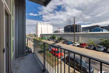 A balcony with a view of a parking lot and industrial buildings.